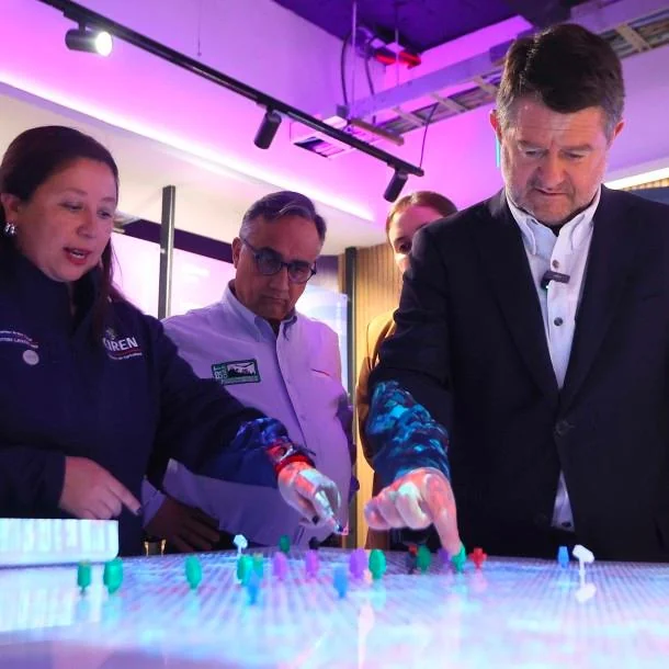 Governor of Santiago and colleagues interacting with the tactile urban-planning table, placing colored markers on the illuminated city grid.