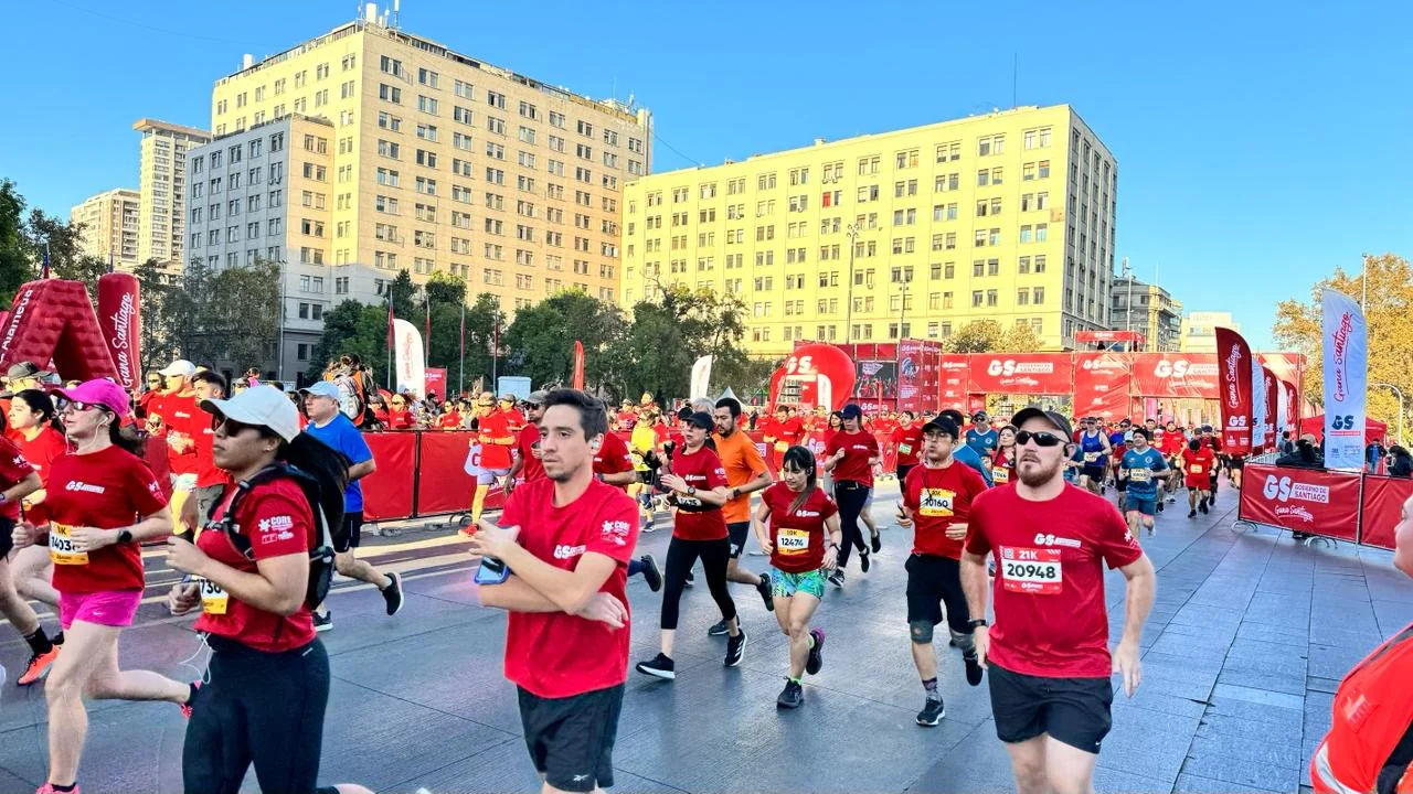 Runners in red Maratón de Santiago shirts passing through Plaza de la Ciudadanía near La Moneda.